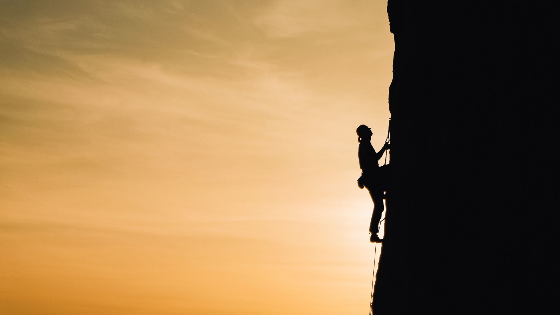 Imagem de um homem escalando uma montanha.