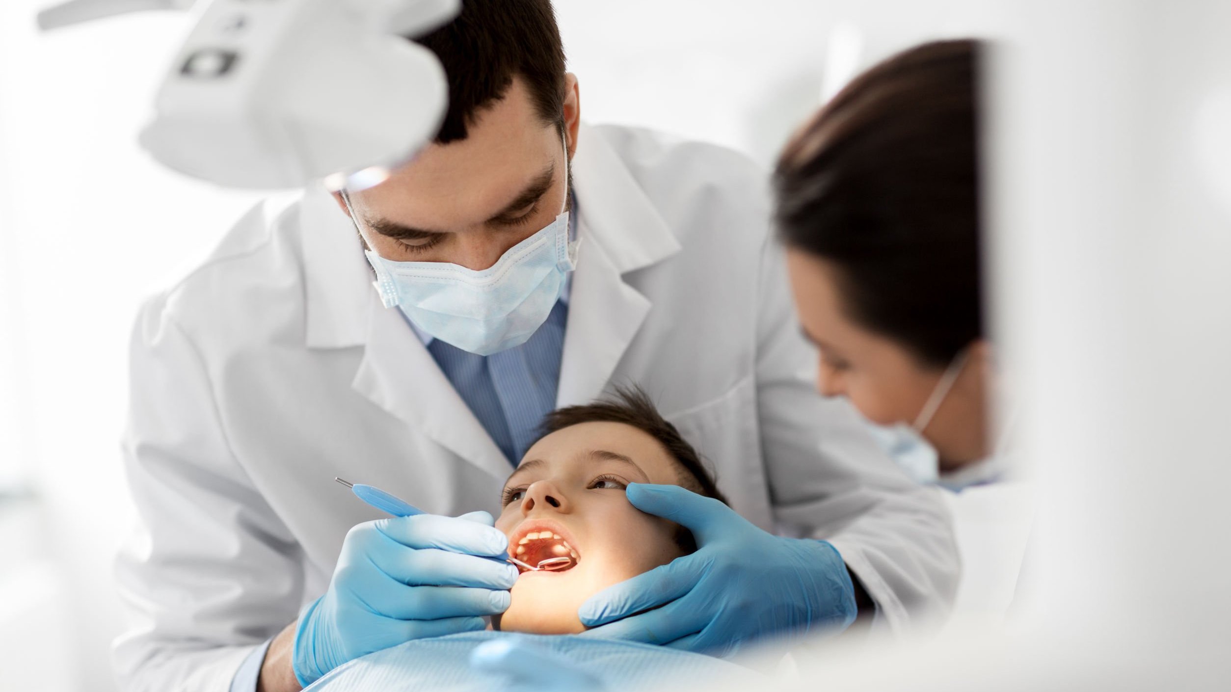 Dentista examinando dentes de criança em consultório