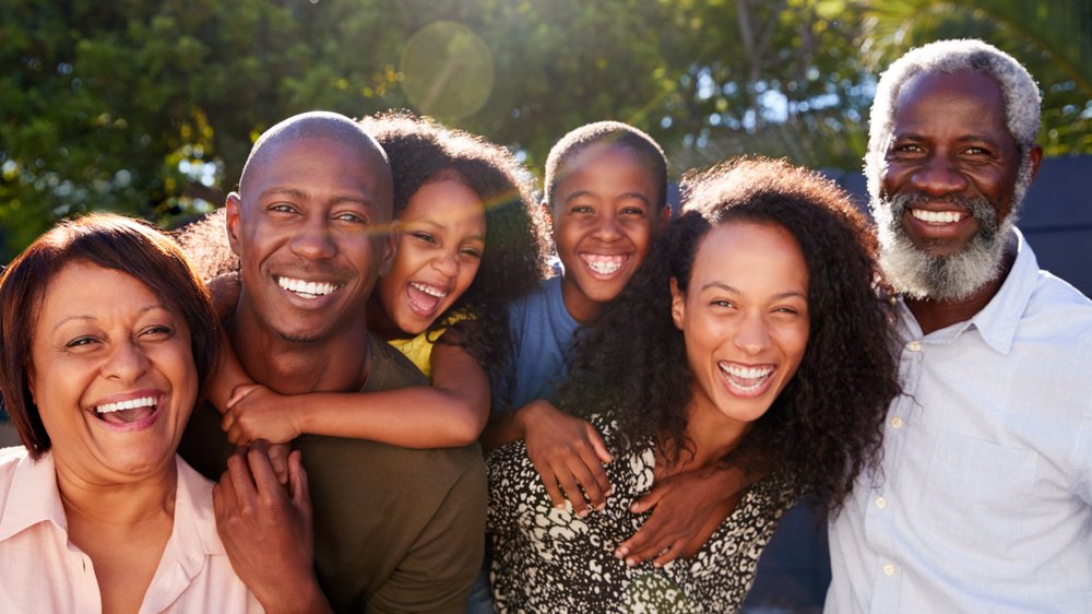 Grande família negra sorrindo e se abraçando ao ar livre