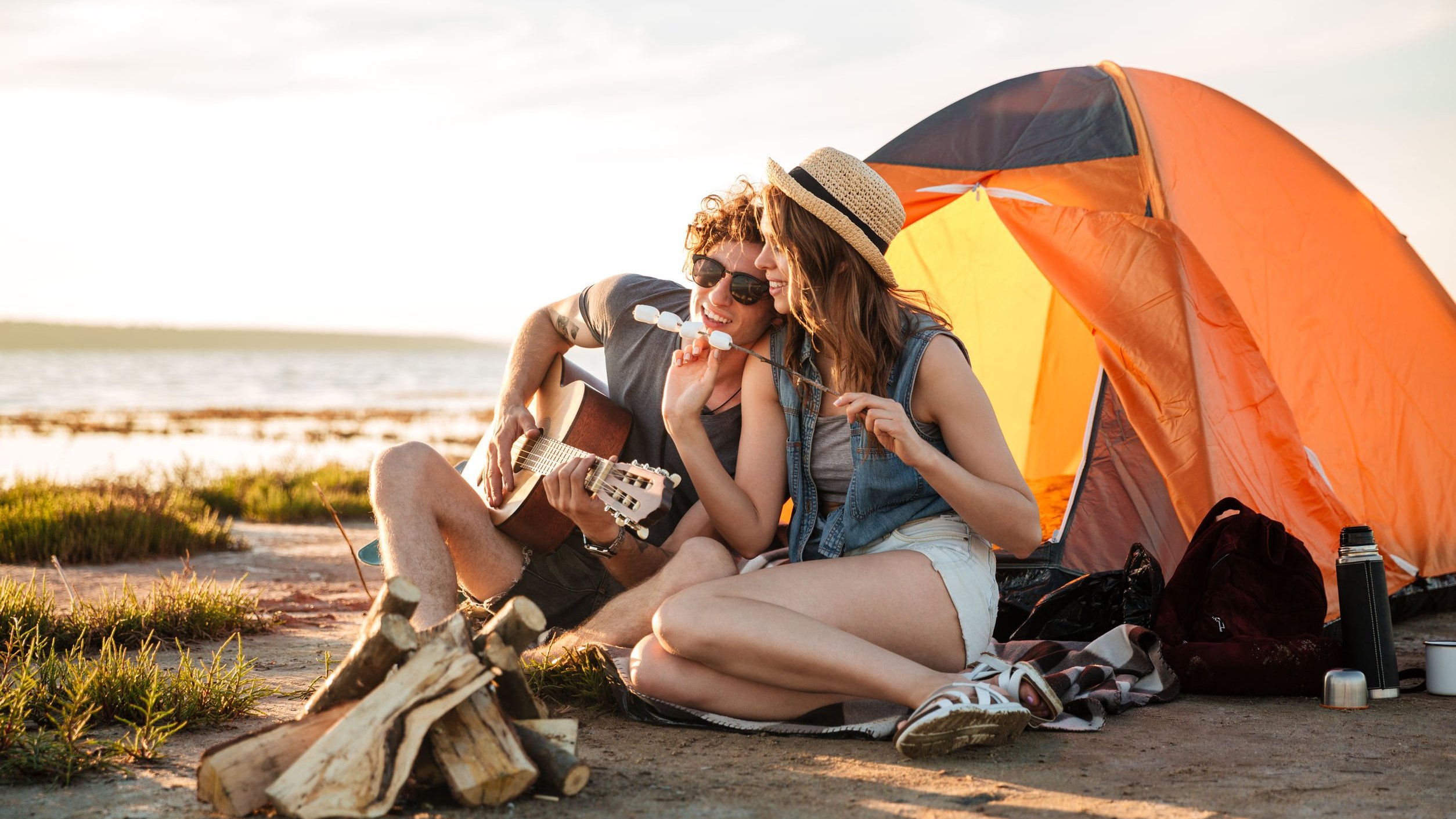 Casal na praia tocando violão e comendo Marshmallow