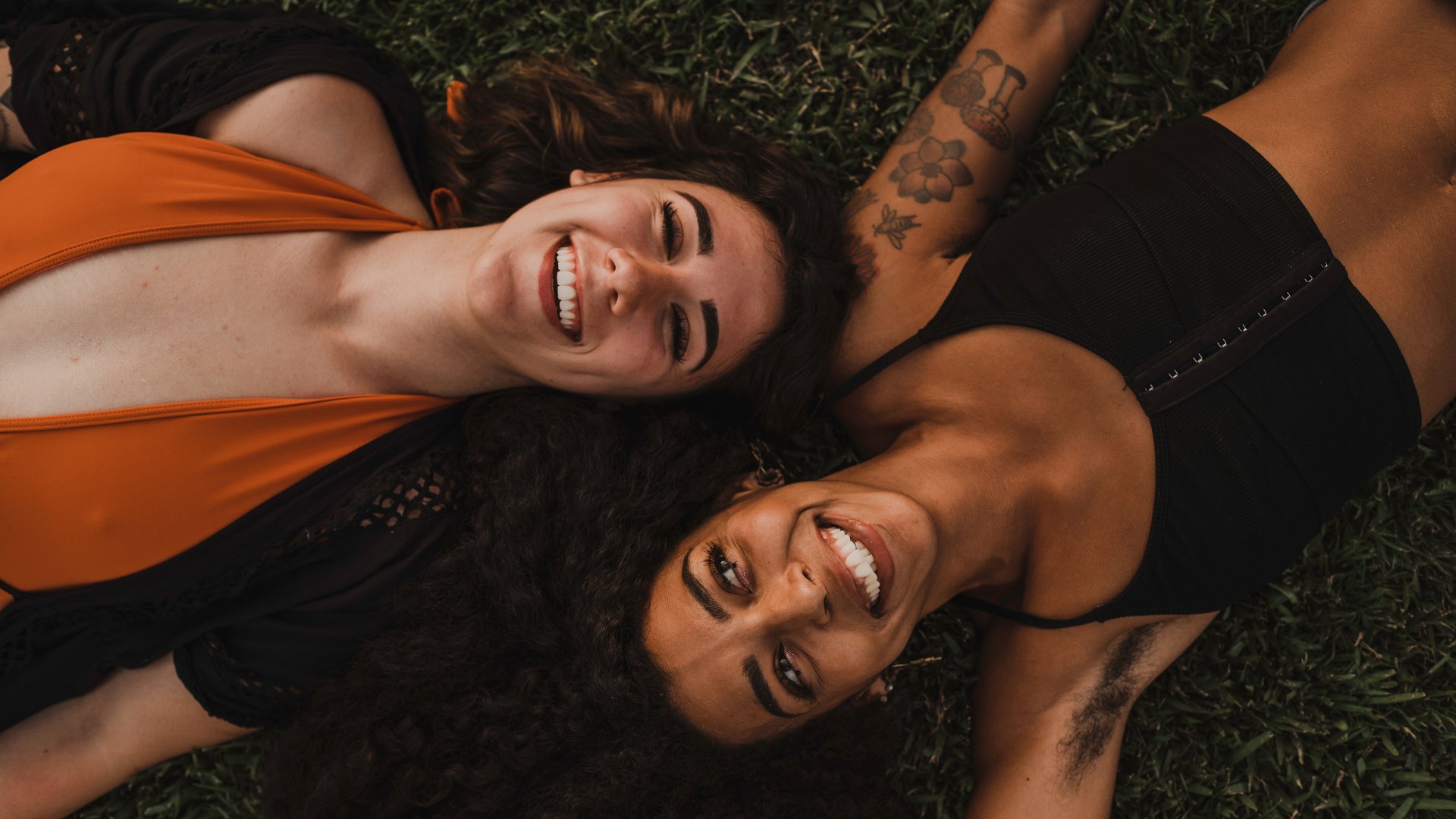 duas mulheres deitadas na grama sorrido