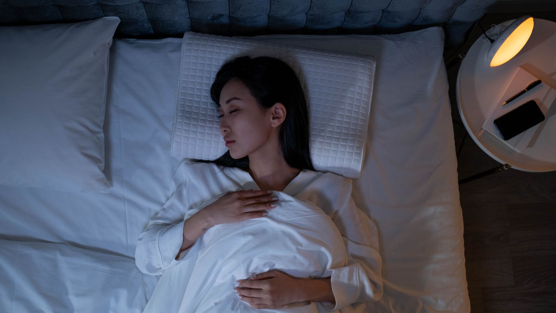 Imagem vista de cima de uma mulher na cama dormindo tranquilamente