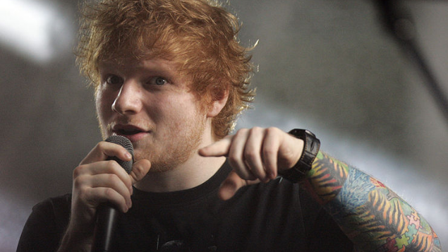 Eva Rinaldi no Canva Ed Sheernan com um microfone na mão