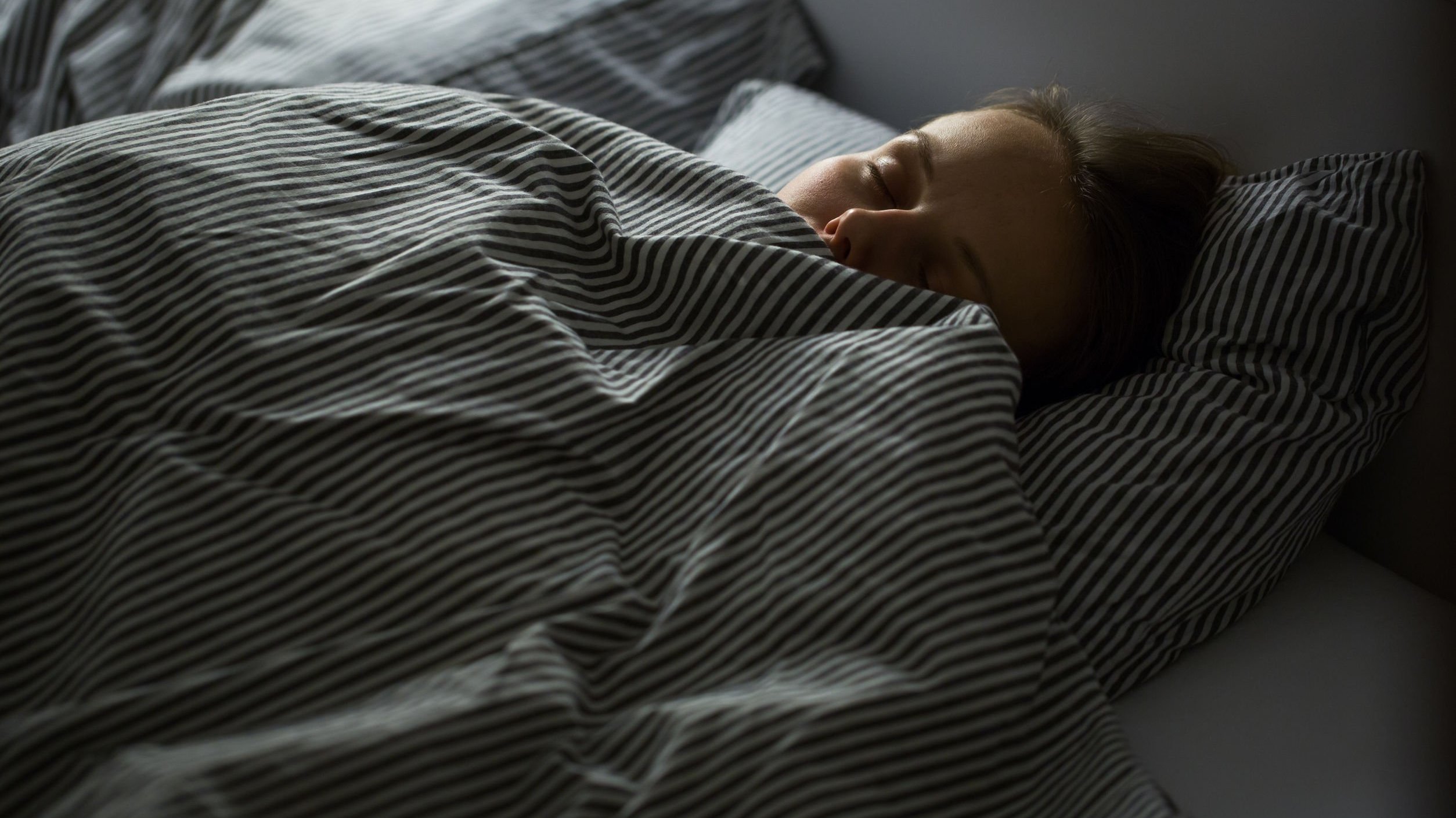 Mulher deitada na cama de olhos fechados