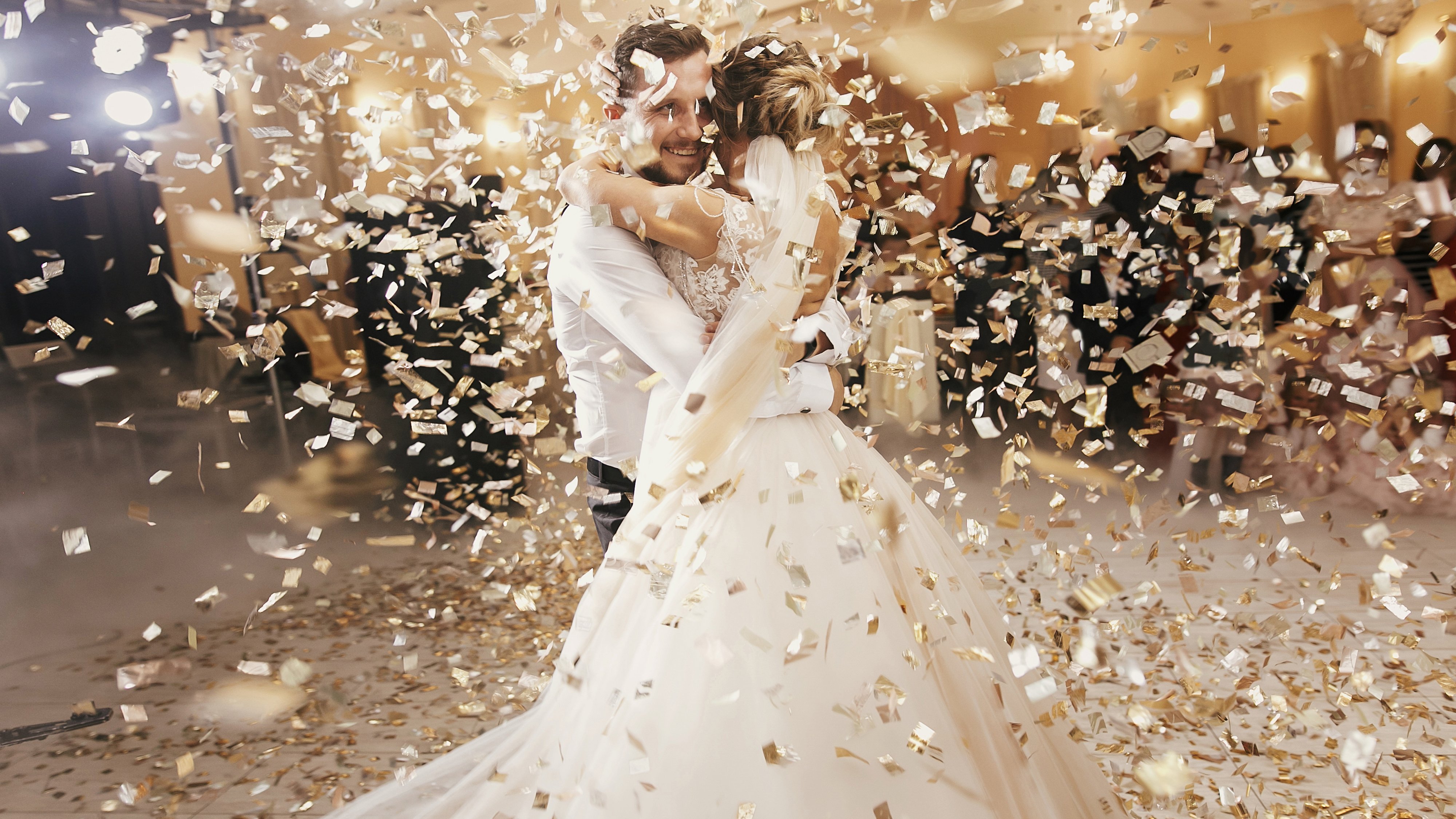 Homem e mulher com roupas de casamento sob uma chuva de confete.