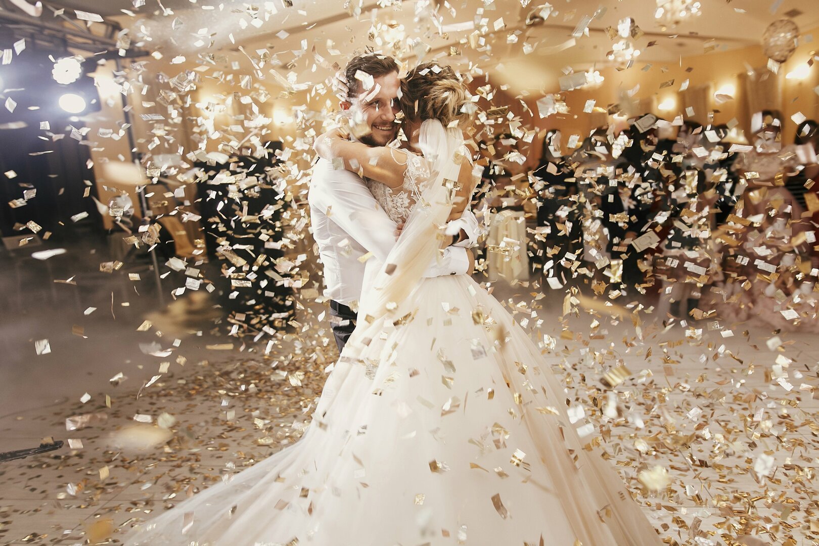 Homem e mulher com roupas de casamento sob uma chuva de confete.