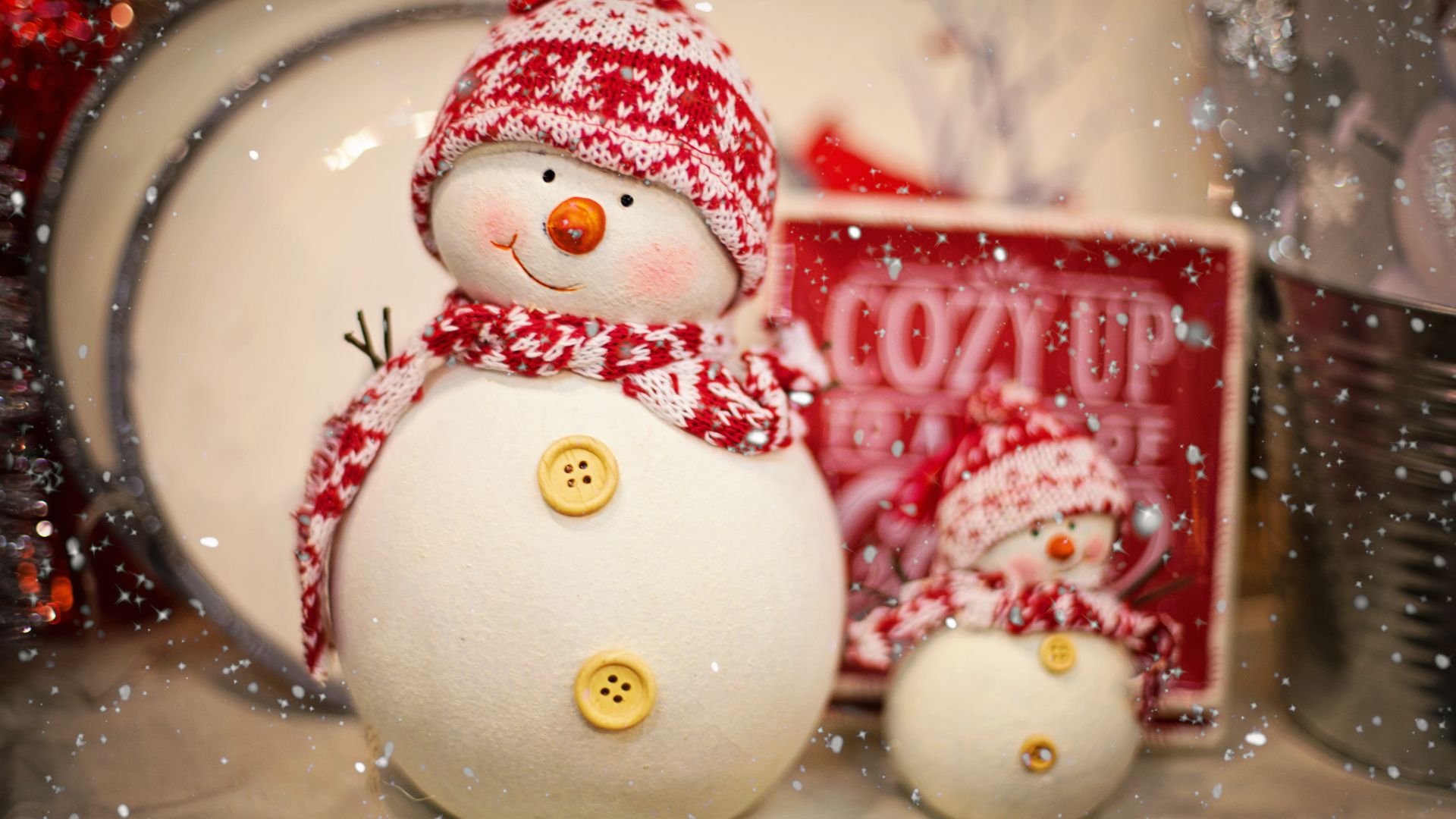 Imagem de dois bonecos de neve vestindo cachecol e gorro de lã nas cores vermelho e branco.
