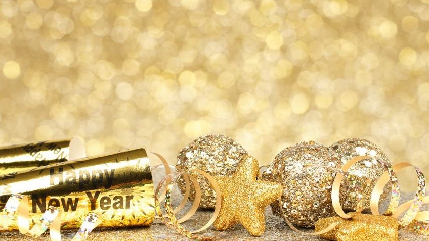 Véspera de ano novo com confetes e decorações douradas em um fundo dourado cintilante.