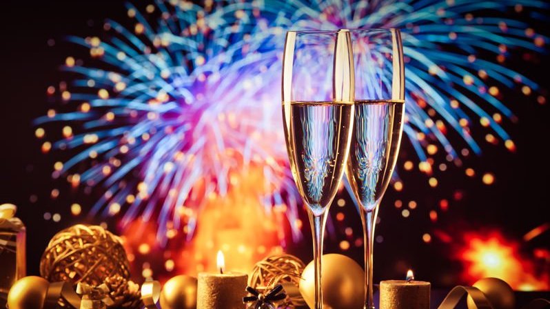 Duas taças de champanhe contra as luzes dos fogos de artifício celebrando o Ano Novo.