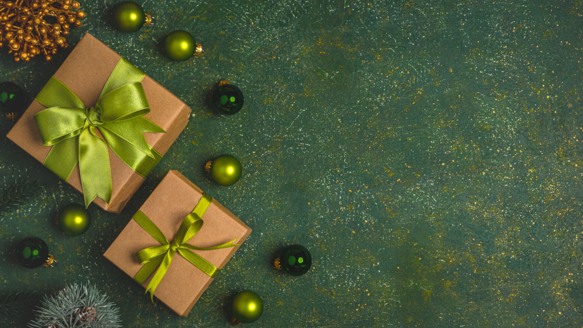 Imagem de fundo verde. Ao lado esquerdo da tela duas caixas de presentes embrulhadas em papel pardo e decoradas com laços na cor verde. Completam a imagem, bolas de natal na cor verde.