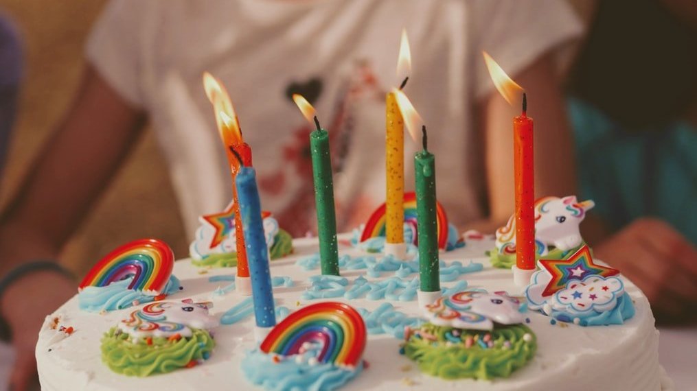 Bolo de aniversário de unicórnio com velas acesas.