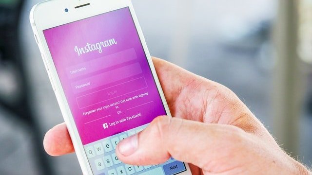 Mão segurando celular na página de login do Instagram