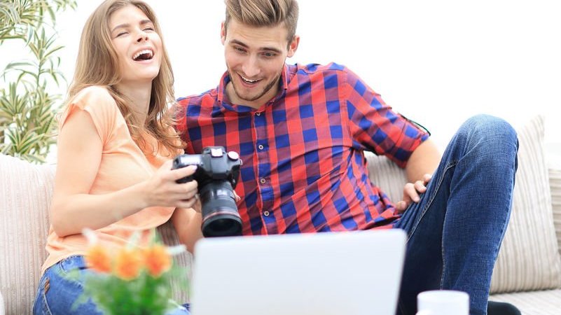 Jovem casal vendo fotos na câmera fotográfica