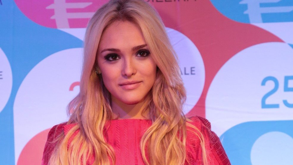 Isabelle Drummond com cabelo loiro e vestido rosa