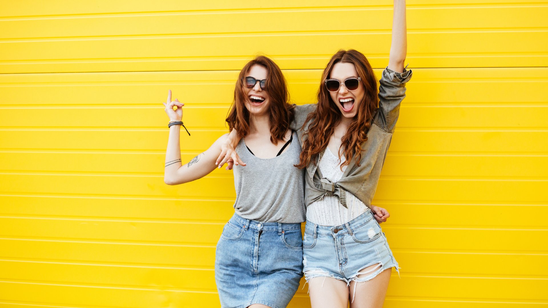 Duas amigas felizes se abraçando em um fundo amarelo