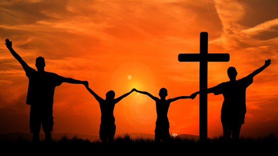 Silhueta de pessoas ao pôr do sol, juntamente com uma cruz