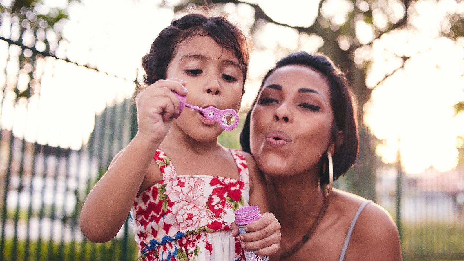 Mãe e filha soltando bolhas de sabão.