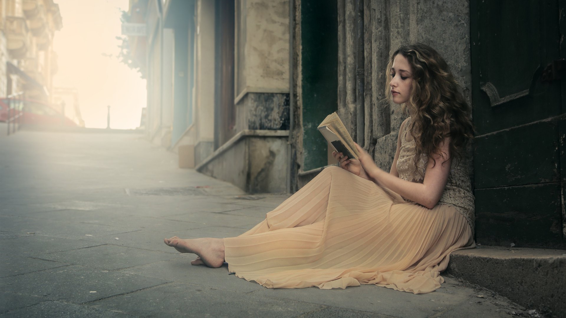 Mulher sentada na calçada lendo livro