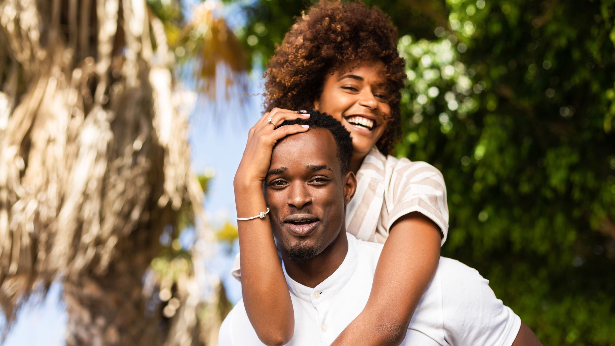 Mulher sorrindo e olhando para o lado  nas costas da homem que está sorrindo