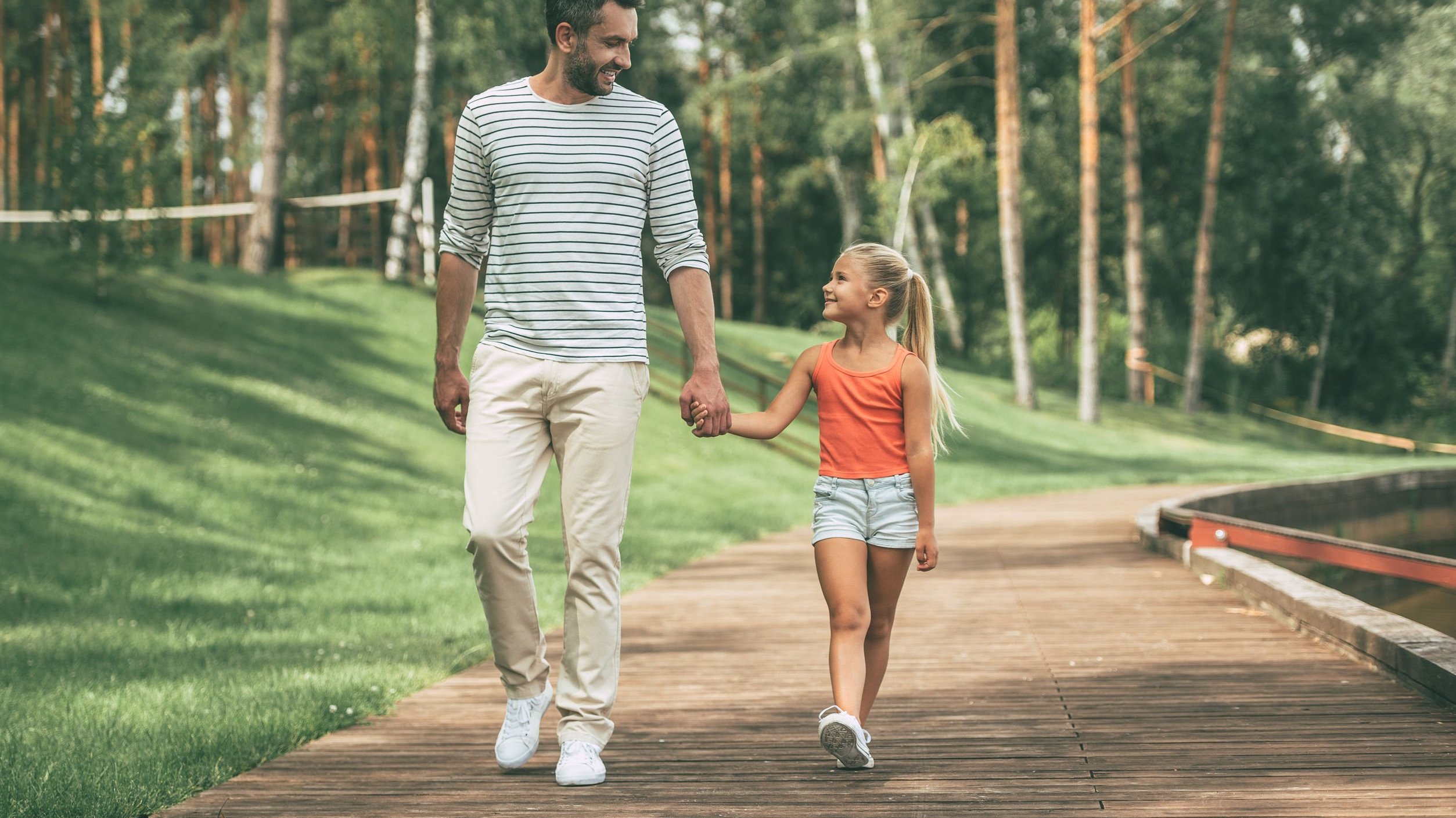 Pai andando de mãos dadas com a filha.