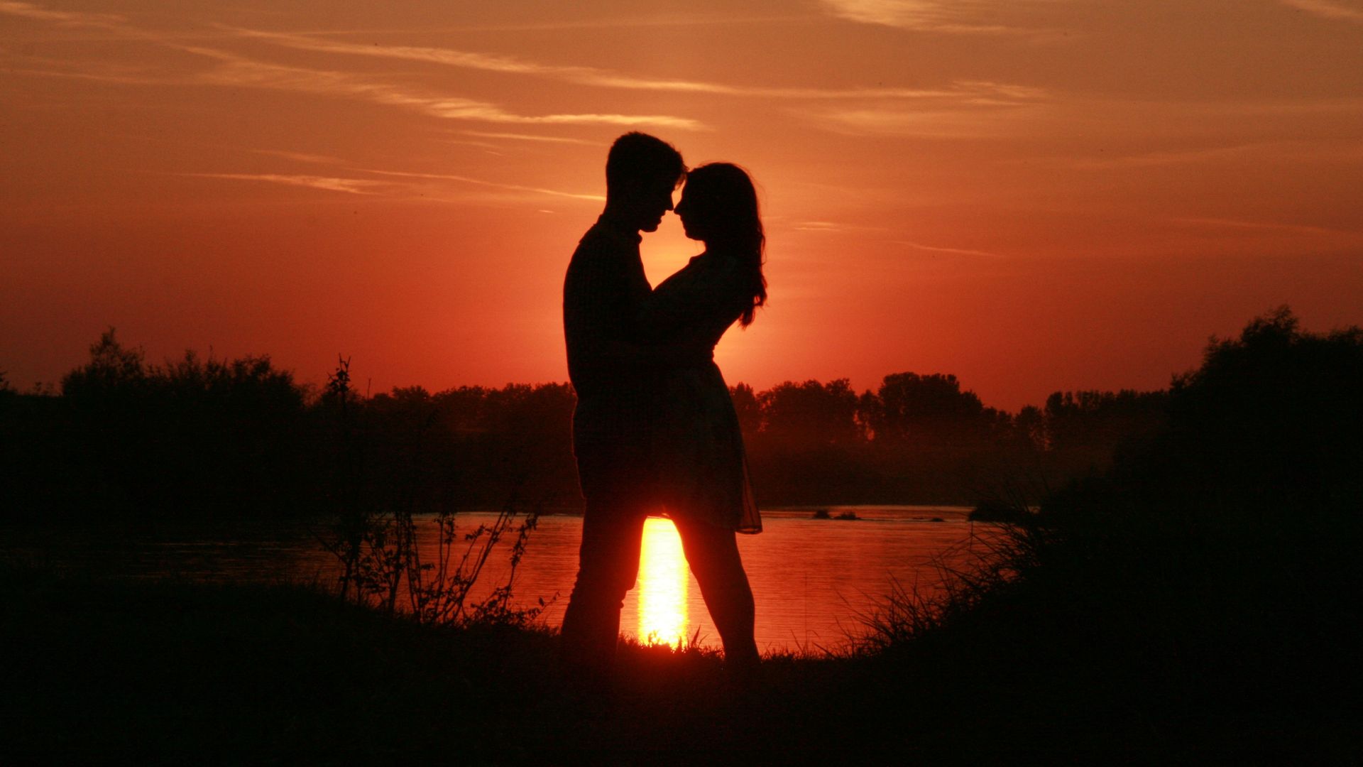 Imagem de um casal abraçado ao pôr do sol