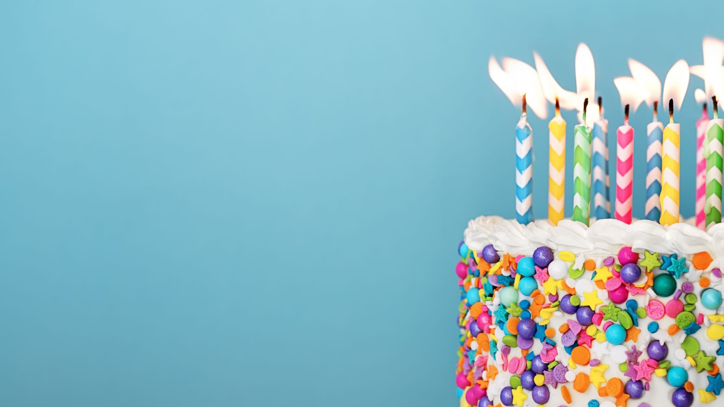 Velas coloridas sobre bolo de aniversário decorado