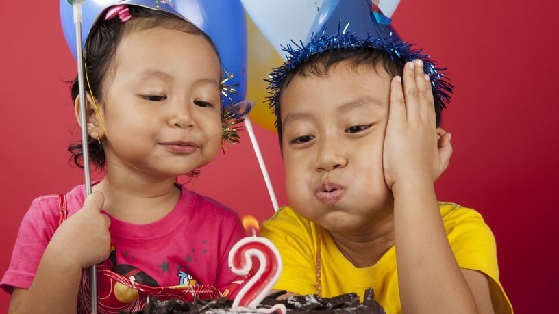 Irmãos assoprando velinha de bolo de aniversário