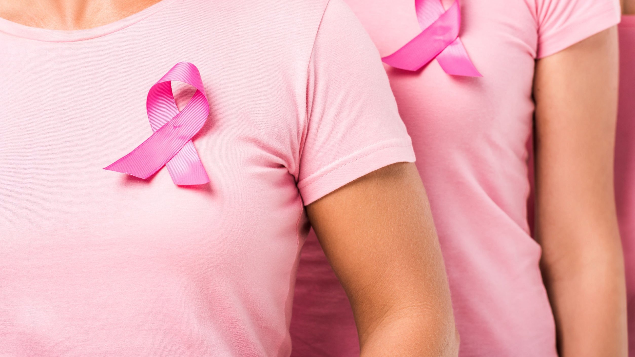 Mulheres com camisetas cor de rosa representativas da luta contra o câncer de mama.