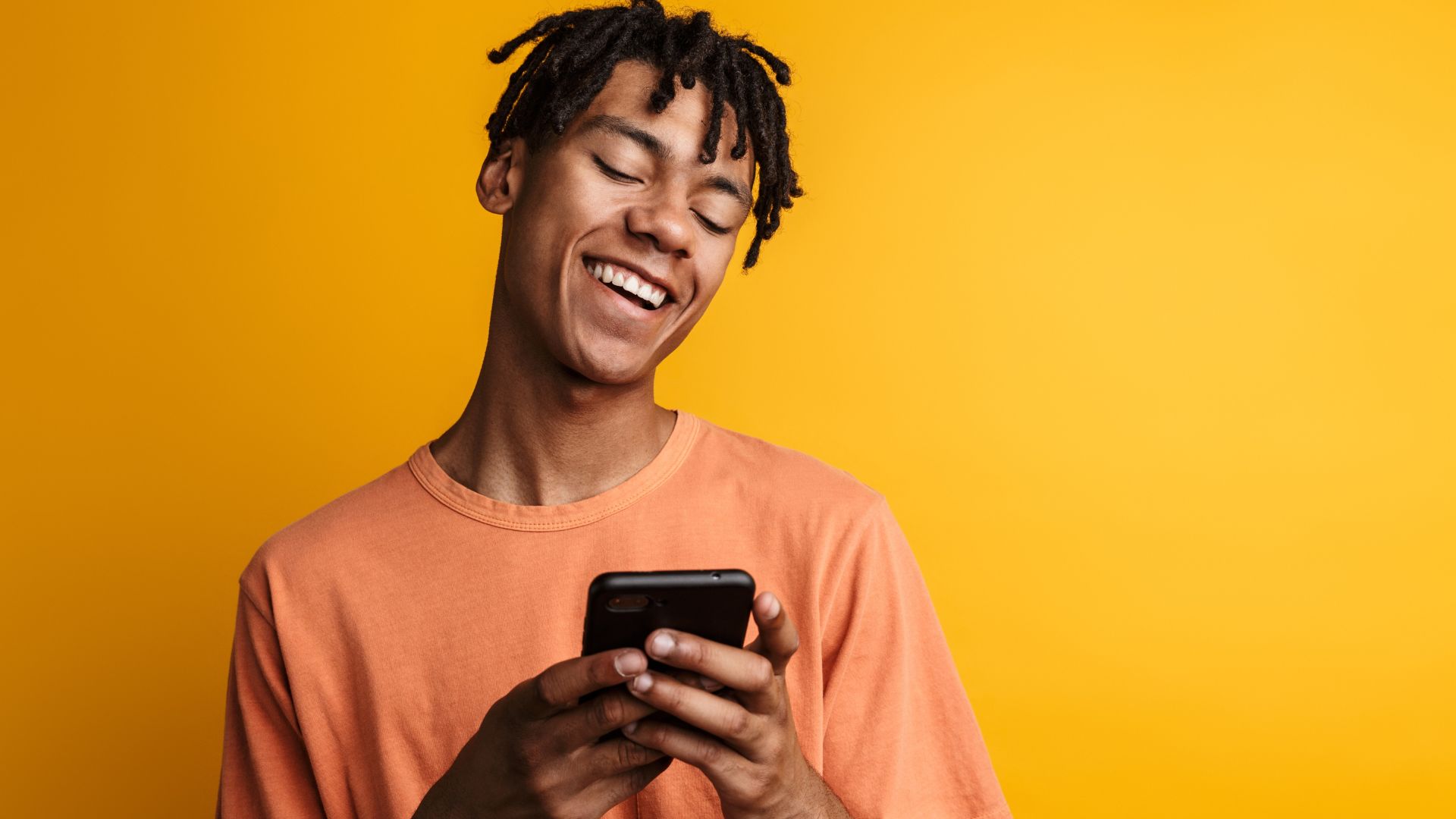 Imagem de um homem olhando para o celular e sorrindo.