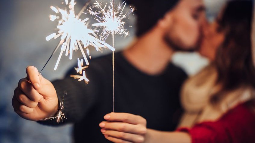 Casal se beijando e segurando vela faísca