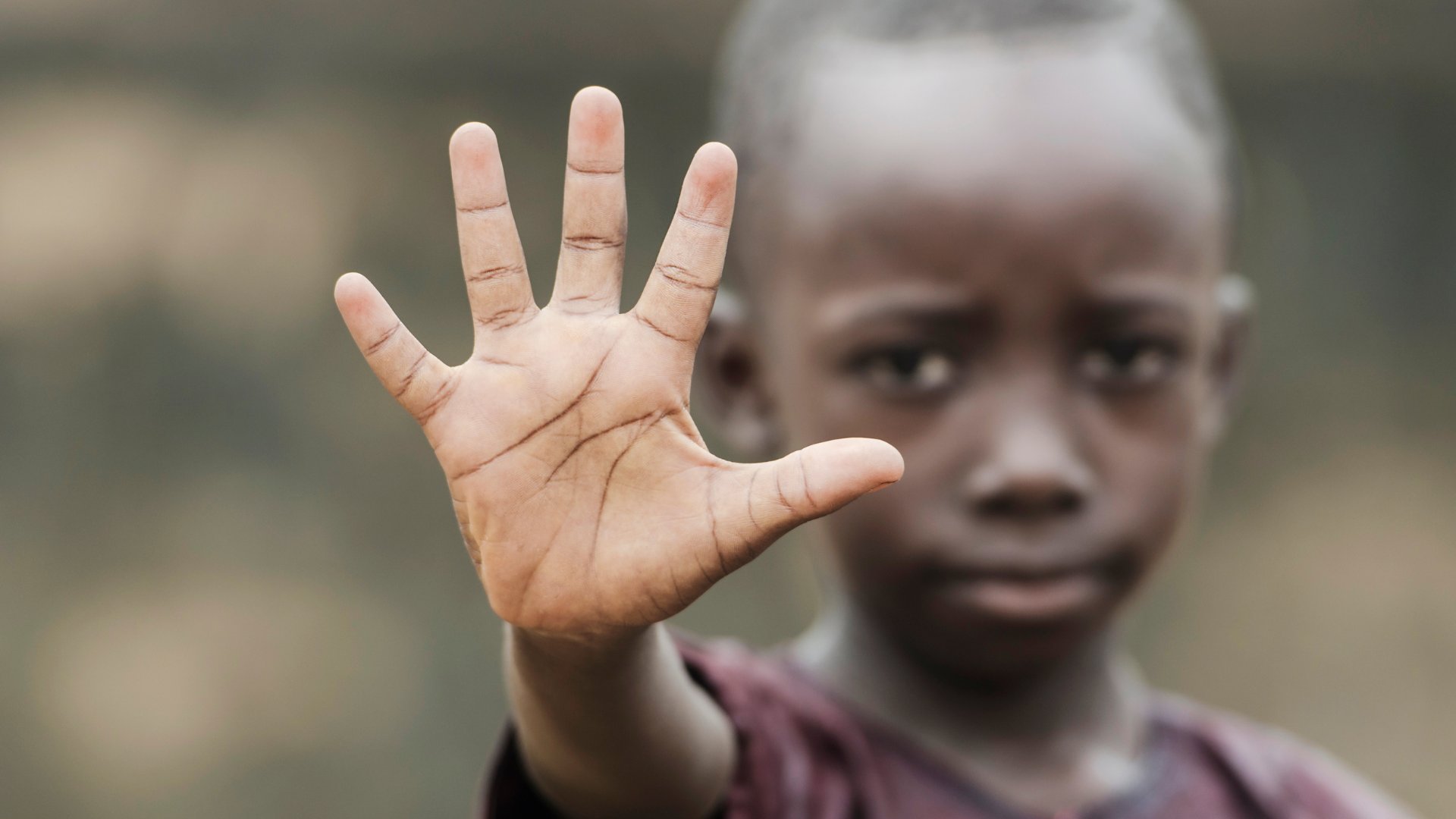 Uma criança negra fazendo o gesto de 'pare' com a mão