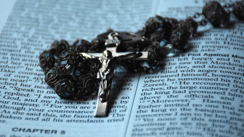 Bíblia e pingente de crucifixo em cima