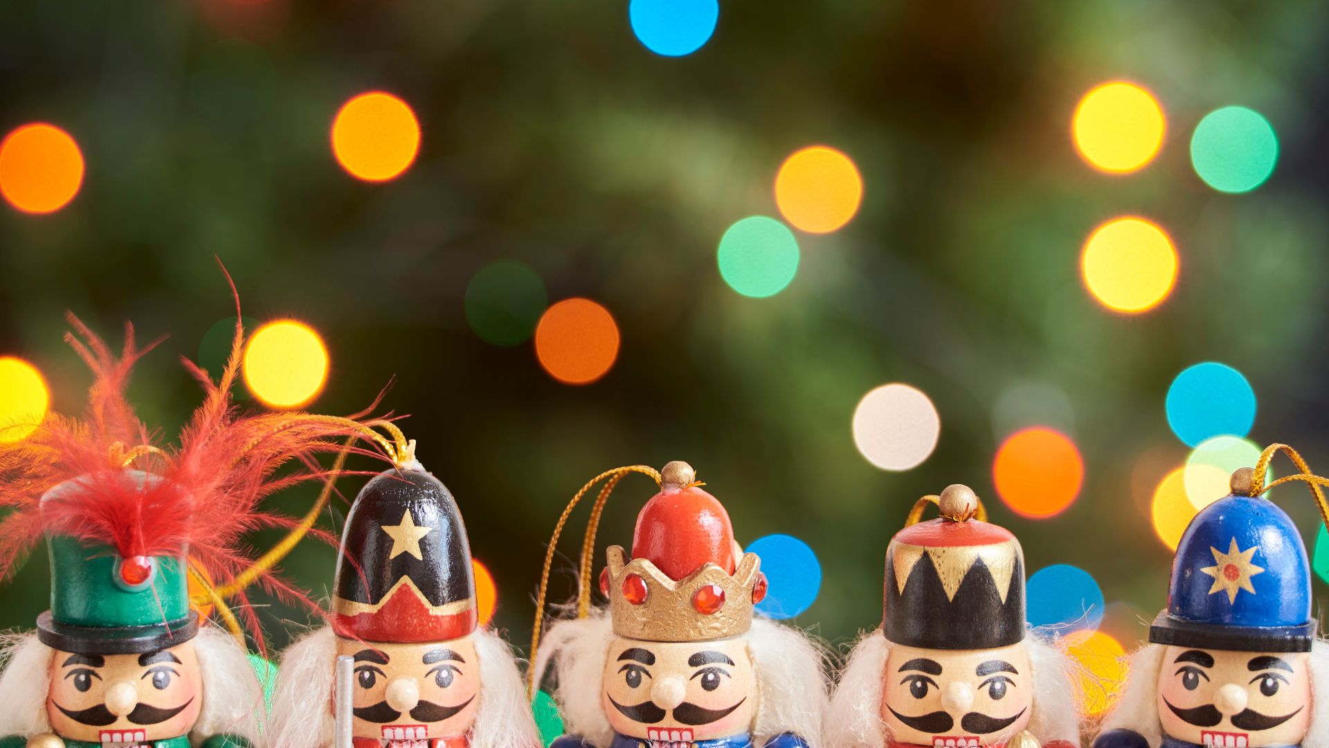 Imagem de fundo verde com bolas coloridas. Em destaque, vários enfeites de bonecos para pendurar na árvore de Natal.
