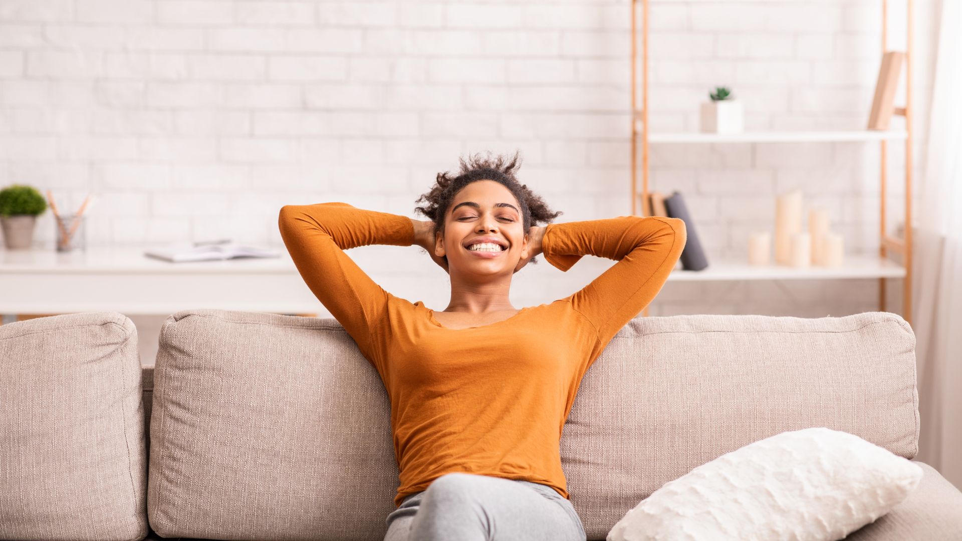 Mulher relaxando no sofá e sorrindo com feição de descontração