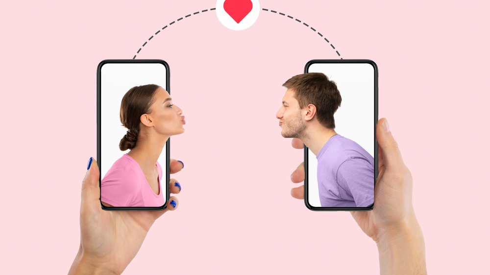 Mãos segurando celulares com homem e mulher se olhando e um coração entre eles