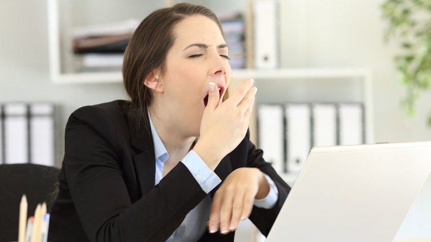 Mulher bocejando na frente do computador.