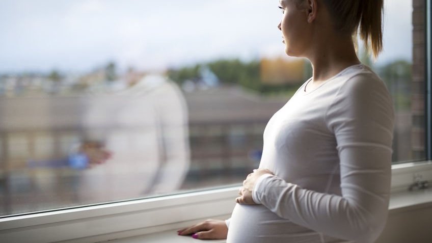 Mulher grávida com a mão na barriga