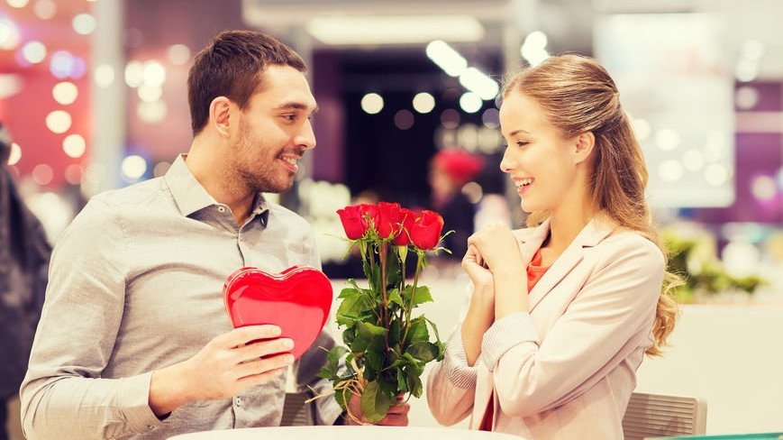 Homem dando flores vermelhas e presentes para uma mulher
