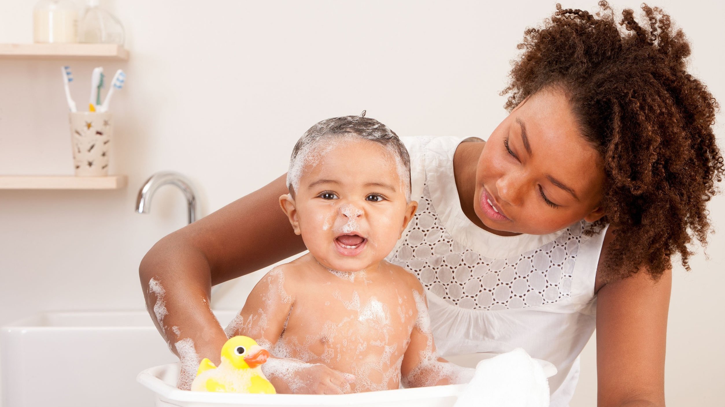 Mulher dando banho em um bebê na banheira