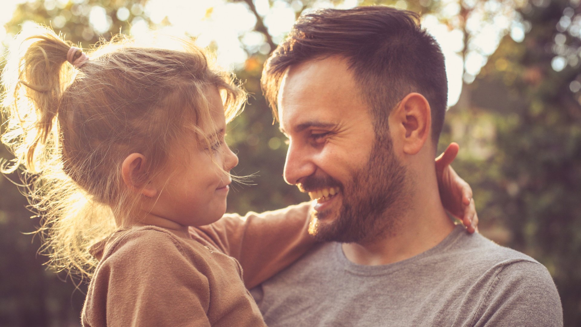 Pai e filha pequena abraçados e sorrindo