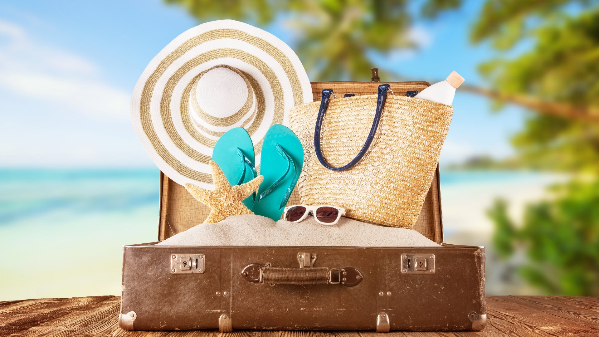 Jag_cz / Getty Images Pro / Canva Mala de viagem e praia ao fundo