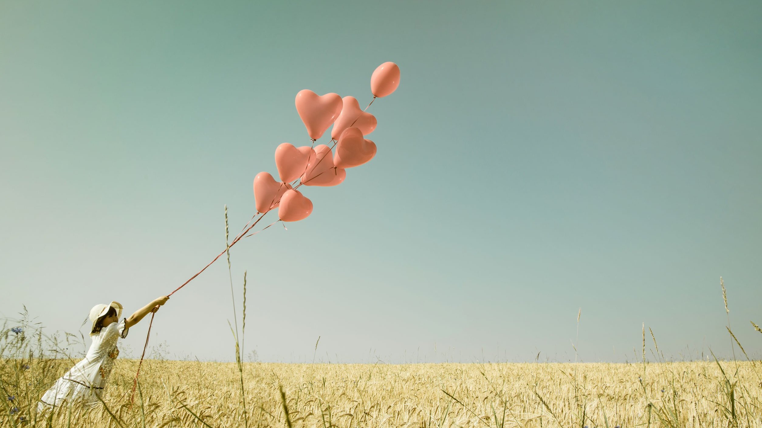 Menina segura balões em formato de coração