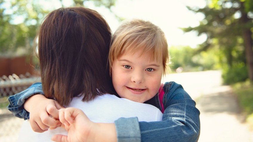 Imagem de uma menina abraçando sua mãe e sorrindo