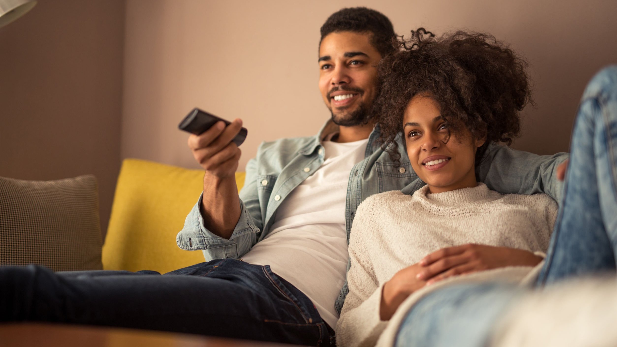 Casal sentado no sofá assistindo televisão