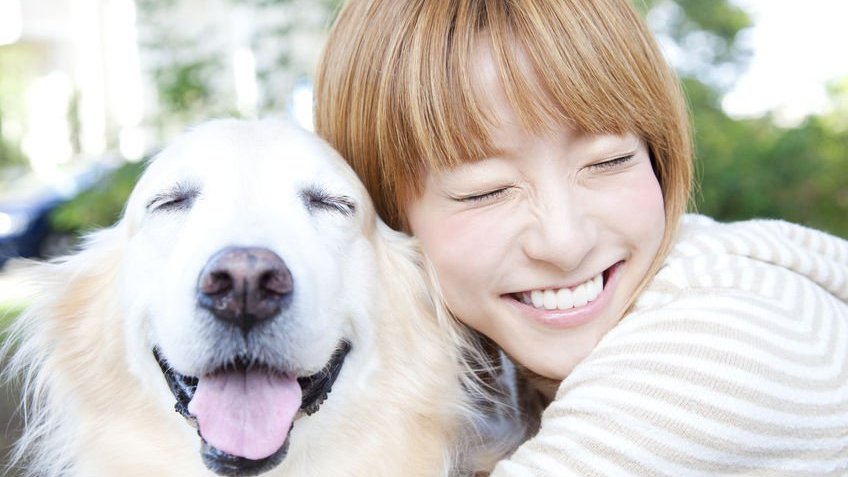 Menina sorrindo e abraçando cachorro