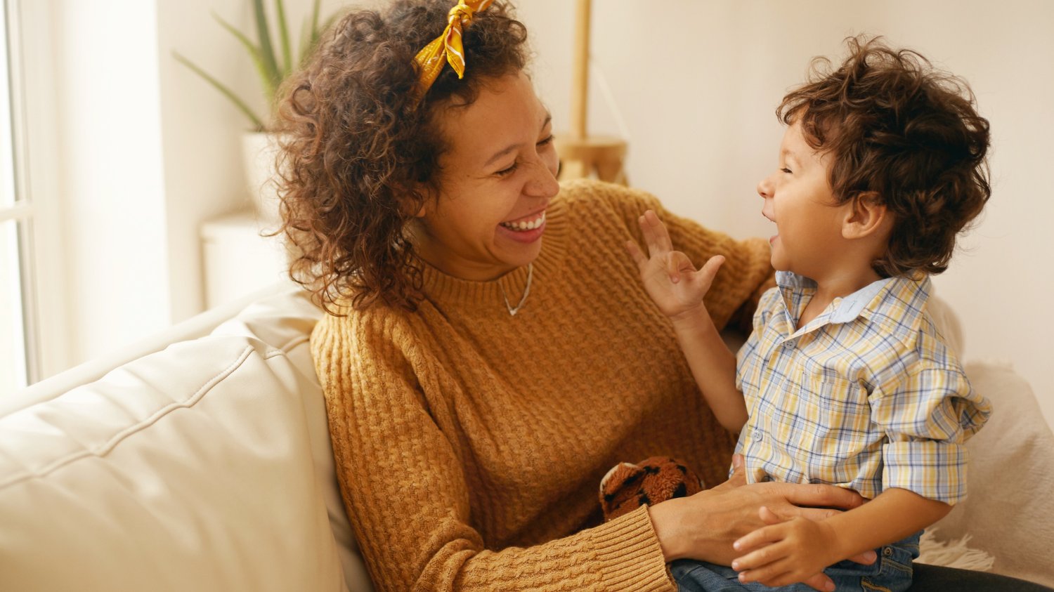 Uma mãe negra com seu bebê no colo. Ambos estão sorrindo.