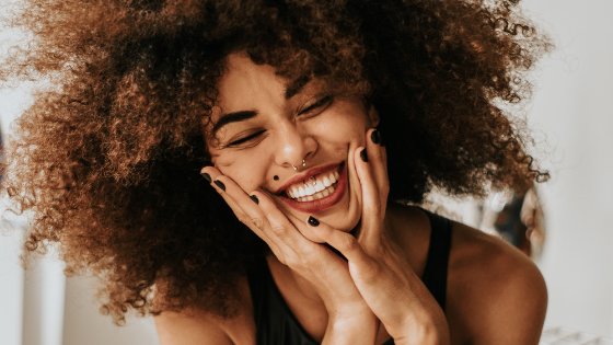 Mulher sorrindo com as mãos no rosto