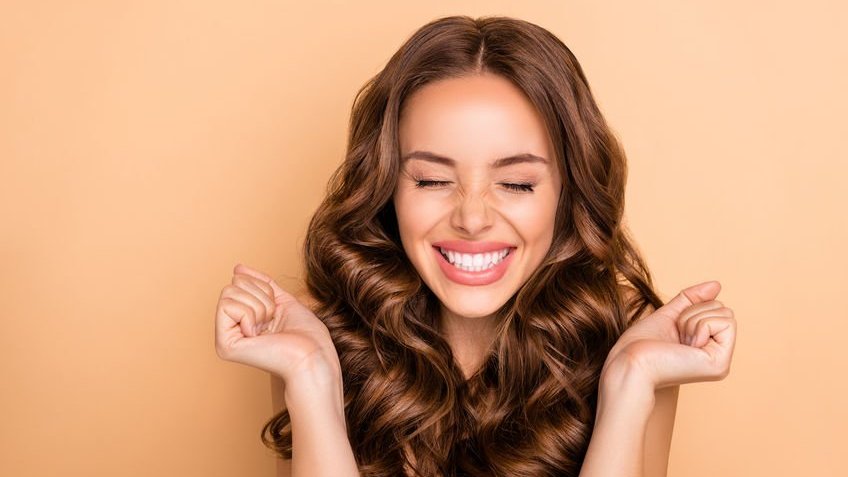 123RF | Roman Samborskyi Mulher com expressão feliz e mãos fechadas