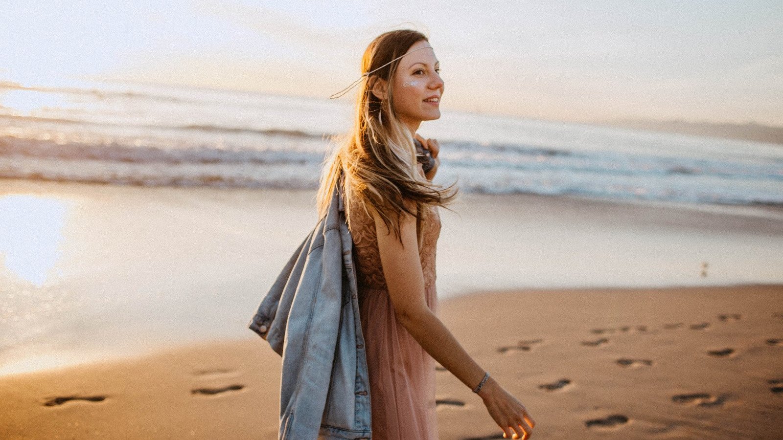 Mulher branca e loira na praia, com expressão sorridente.