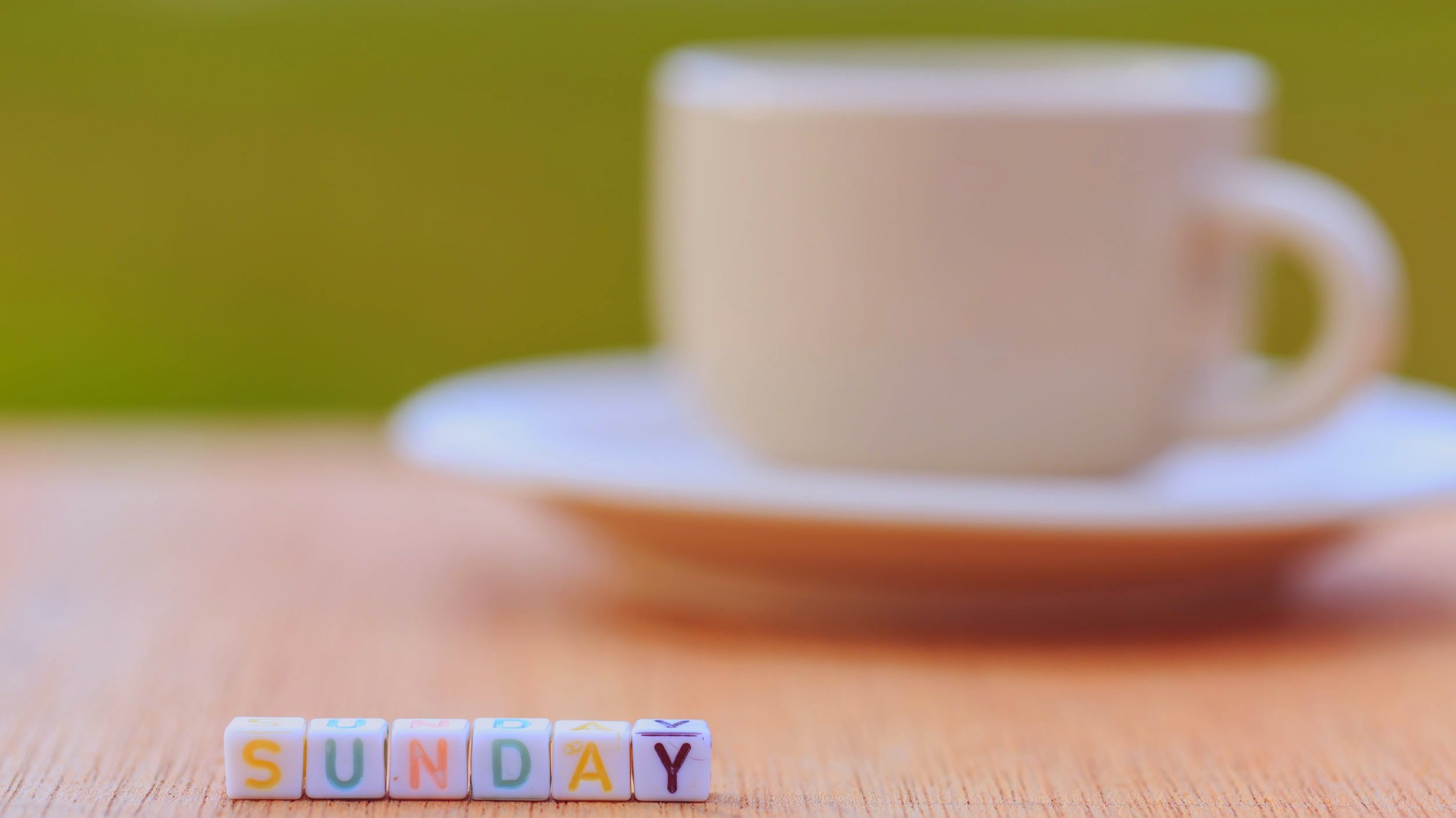 Mesa com xícara branca e miçangas coloridas formando a palavra